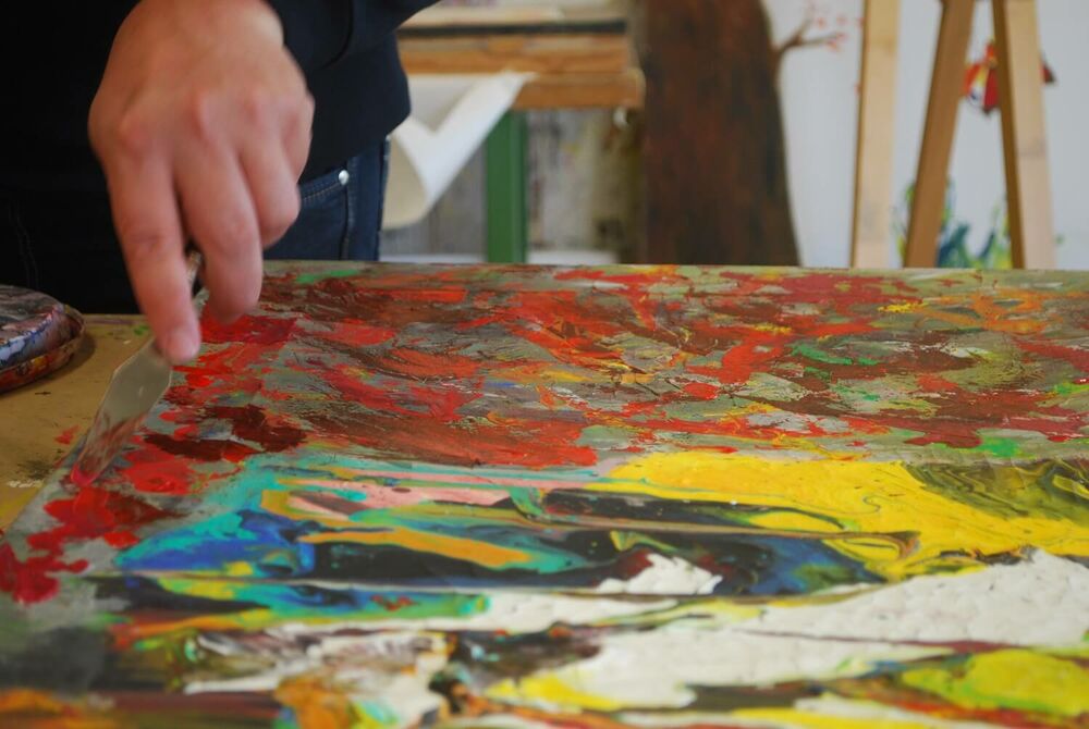 Die Hand von einem Künstler zeigt auf Farben und Strukturen in einem Gemälde